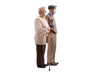 Senior couple with walking cane wearing medical face masks