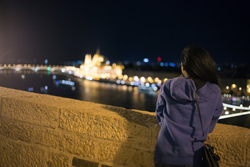 Fototapeta na wymiar Beautiful young girl looks at the parliament building in Budapest at night