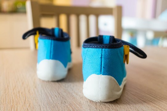 Closeup Shot Of The Blue Baby Shoes On A Wooden Table In The Room