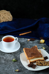 Bread slices with chocolate cream and a cup of tea on the marble table