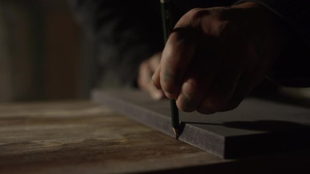 Mann zeichnet Linie auf eine Holzoberfl&auml;che