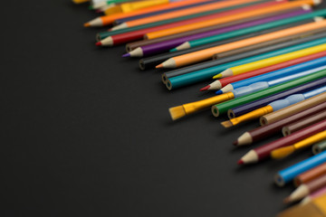 Coloured pencils on black background with copy space. Education, creativity, art.