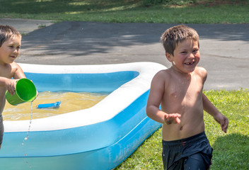 Laughing boy runs as his brother tosses water