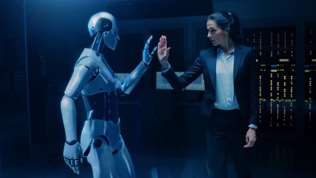 Beautiful, Confident Female Engineer Touching Hands with Humanoid Robot Activating Collaboration, Teamwork Protocol. Computer Artificial Intelligence Concept: People and Robots Working Together