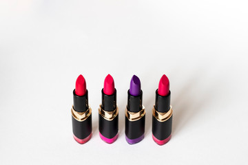 A palette of colored matte lipsticks from violet to bright pink in the center of a white background.