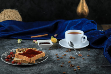 Bread toast with berry jam and a glass of tea on a blue table