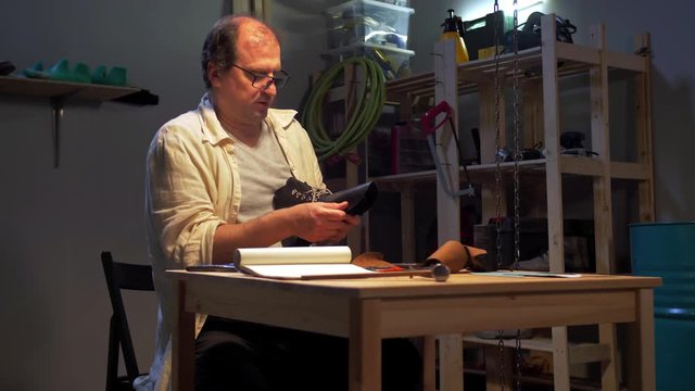 Man sits and creates a shoe in the workshop