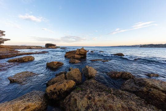 Rocky shoreline around Bondi beach, Sydney, Australia. Sunset near the famous surfer beach. Sunset over the pacific ocean. Sun reflecting in the smooth water. Breathtaking colorful sea side sunset. 