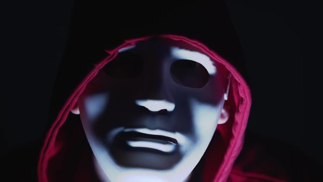 Man wearing a scary theatrical mask looking at camera with threatening eye look