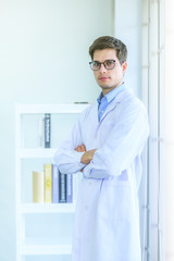 Male scientist/doctor standing and crossing his arms beside windows. Portrait shoot in natural light.