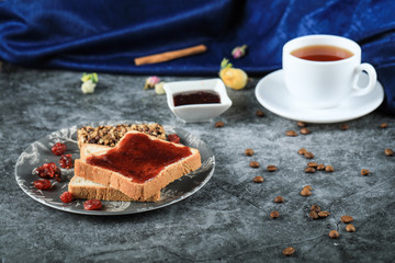 A cup of tea with chocolate toast and berry jam on a marble table