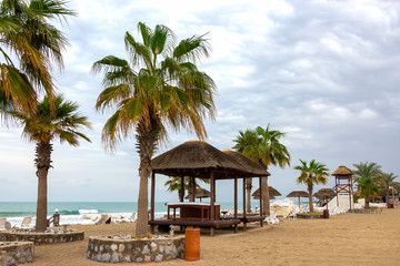 Obraz premium Empty deserted beach with umbrellas and sunbeds. Overcast weather. Gulf Coast. Ocean view. Travel concept