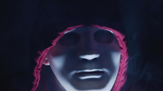 threatening look of the man with white mask and hoodie. Anonymous hacker sending threatening message