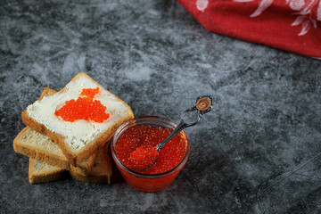 Red caviar in a glass jar and on bread slices, top view