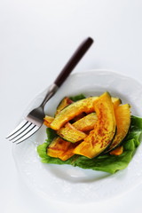 Pan fried pumplin slices on white dish