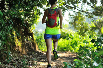 Fototapeta premium Young woman trail runner running in sunrise tropical forest