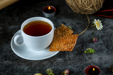 A cup of tea with crackers on black marble