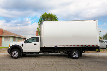 An unbraded commercial grade and heavy duty moving truck or furniture delivery vehicle parked infront of a residential home.
