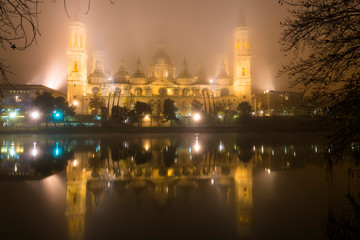 Obraz premium Basilica del Pilar illuminated at night reflected in the Ebro River, Zaragoza Spain