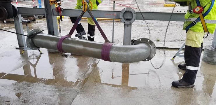 Riggers move the pipe using two chain blocks