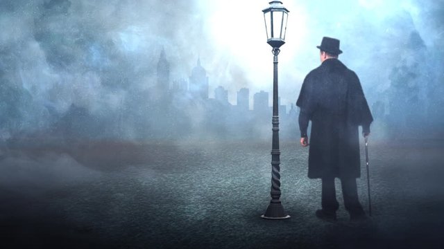 Old Fashioned Man Standing by a Streetlamp in the Fog 4K features a man in a caped coat with a walking stick standing in a foggy atmosphere next to a street lamp.
