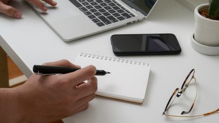 Cropped shot of university student take short note on notebook while reading text