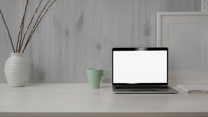 Close up view of trendy workspace with blank screen laptop on marble desk with white modern rustic wall