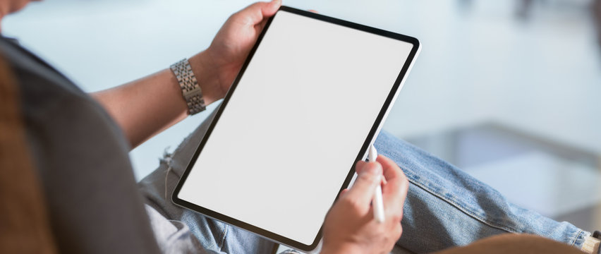 Cropped shot of a man sitting at modern living room and using vertical blank screen tablet
