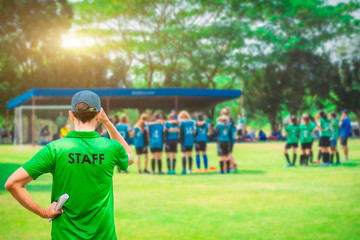 Fototapeta premium Staff coaches who stand to watch athletes compete on the side of the field. Rear view.