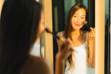 Portrait beautiful young asian woman make up with cosmetic powder and lipstick on her face facial in bathroom