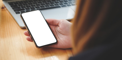 Cropped shot view of woman hands holding smart phone with blank copy space screen for your text message or information content, female reading text message on cell telephone during in urban setting.