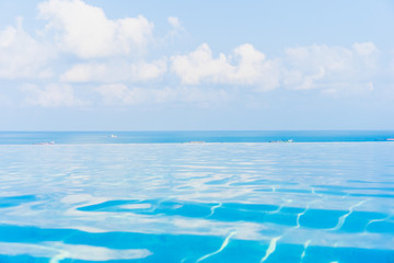Fototapeta premium Beautiful infinity outdoor swimming pool with sea ocean view around white cloud blue sky