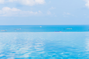 Beautiful infinity outdoor swimming pool with sea ocean view around white cloud blue sky