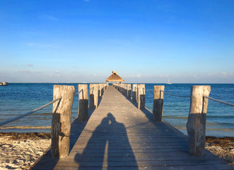 shadow of couple on pier overlooking ocean