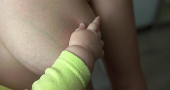 Newborn baby's hand holds mother's breast nipple