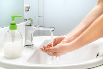 Woman washing her hands with soap at the sink for good hygiene and cleanliness