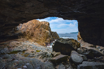 Hidden Cave Landscape beside the ocean with waves crashing again the rock formation during clear summer weather with water seeping into the cave