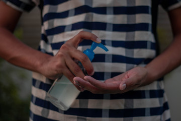 Closeup of a coronavirus infected  man disinfecting his hands with alcohol hand sanitizer from a bottle.Selective focus