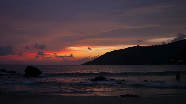 moving sea wave hit rock and sand sea in twilight yellow orange colorful cloudy sky in evening and silhouette cape mountain.