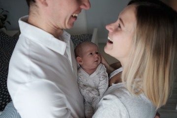 Smiling mother and father holding their newborn baby daughter at home