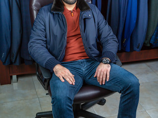 A young man sits in a chair in a men's clothing store