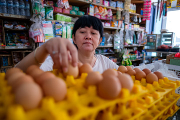 Asian Indonesian women arranging eggs inside small local family-owned business store, locally called warung. Selective Focus.