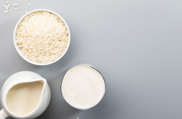Rice milk with rice grains on gray table. Copy space, top view