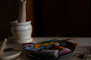Indian fishes decorated with whole spices kept on a wooden dish on a wooden tray. Food photography.