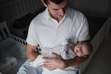 young dad holding a newborn baby in her arms