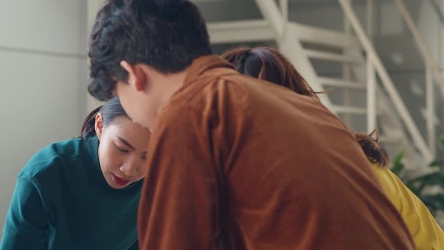 Asian businessmen and businesswomen meeting brainstorming ideas about creative web design planning application and developing template layout for mobile phone project working together in small office.