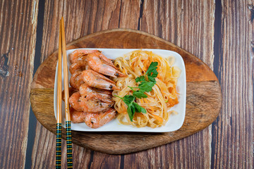 Udon noodles and fried cocktail prawns on a plate.