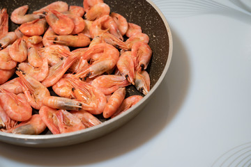 small cocktail shrimps are fried in a pan. 