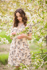 Fototapeta na wymiar Beautiful young girl in a flowered garden