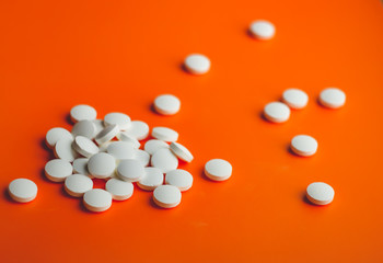 a handful of white pills in the foreground on a bright color background